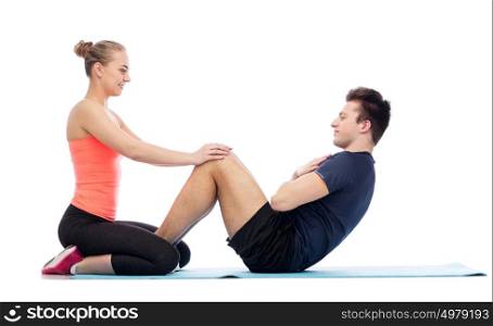 sport, fitness, lifestyle and people concept - happy sportive man and woman doing sit-ups. happy sportive man and woman doing sit-ups