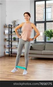 sport, fitness, lifestyle and people concept - happy woman exercising with resistance band at home. woman exercising with resistance band at home
