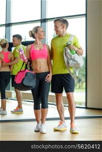 sport, fitness, lifestyle and people concept - smiling couple with water bottles in gym