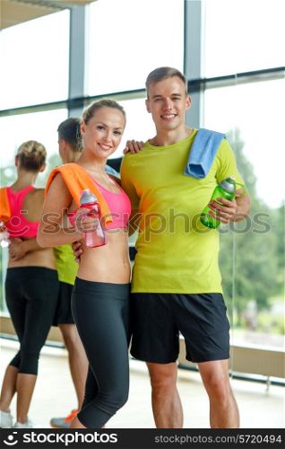 sport, fitness, lifestyle and people concept - smiling couple with water bottles in gym