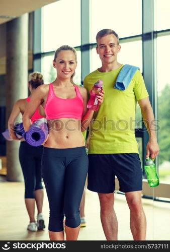 sport, fitness, lifestyle and people concept - smiling couple with water bottles in gym