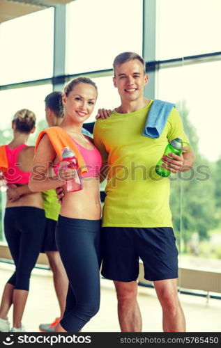 sport, fitness, lifestyle and people concept - smiling couple with water bottles in gym