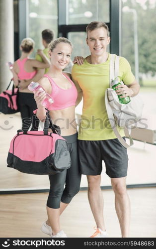 sport, fitness, lifestyle and people concept - smiling couple with water bottles in gym