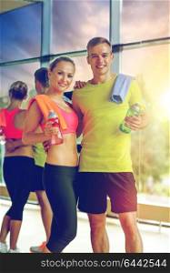 sport, fitness, lifestyle and people concept - smiling couple with water bottles in gym. smiling couple with water bottles in gym