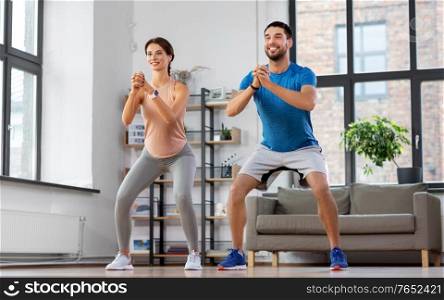 sport, fitness, lifestyle and people concept - smiling man and woman exercising and doing squats at home. happy couple exercising and doing squats at home