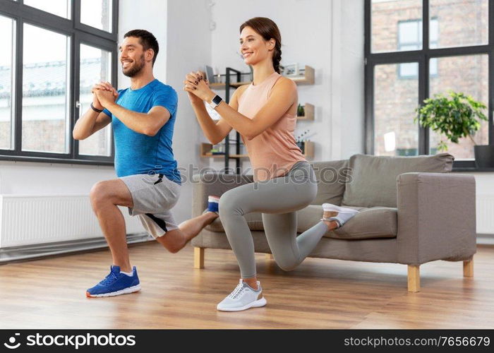 sport, fitness, lifestyle and people concept - smiling man and woman exercising and doing squats in low lunge at home. happy couple exercising and doing squats at home