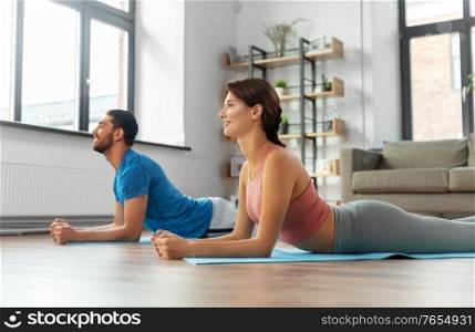 sport, fitness, lifestyle and people concept - smiling man and woman exercising at home. happy couple exercising at home