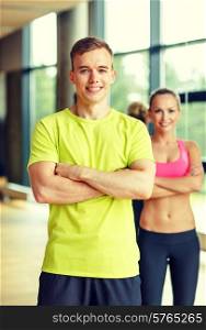 sport, fitness, lifestyle and people concept - smiling man and woman in gym
