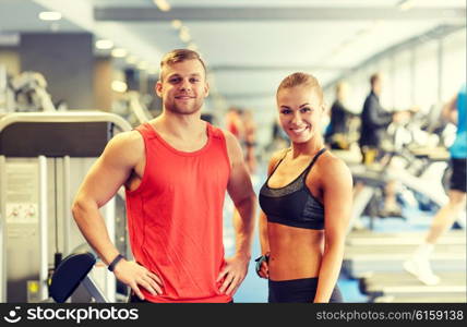 sport, fitness, lifestyle and people concept - smiling man and woman in gym