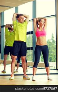sport, fitness, lifestyle and people concept - smiling man and woman stretching in gym