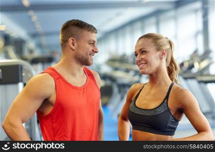 sport, fitness, lifestyle and people concept - smiling man and woman talking in gym