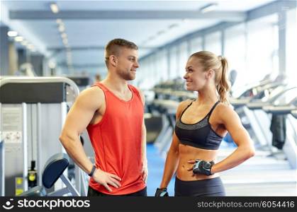 sport, fitness, lifestyle and people concept - smiling man and woman talking in gym