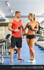 sport, fitness, lifestyle and people concept - smiling man and woman with protein shake bottle and towel talking in gym