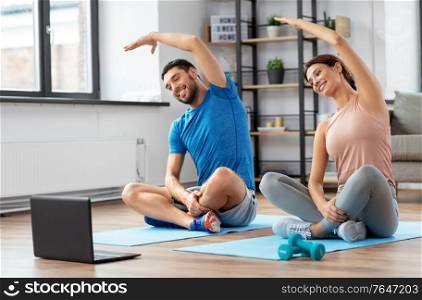 sport, fitness, lifestyle and people concept - smiling man and woman with laptop computer exercising at home. happy couple with laptop exercising at home