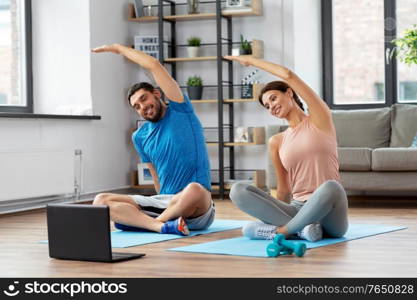 sport, fitness, lifestyle and people concept - smiling man and woman with laptop computer exercising at home. happy couple with laptop exercising at home