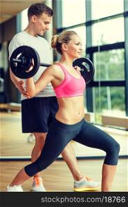 sport, fitness, lifestyle and people concept - smiling man and woman with barbell exercising in gym