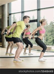 sport, fitness, lifestyle and people concept - smiling man and woman with dumbbells exercising in gym