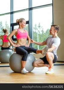 sport, fitness, lifestyle and people concept - smiling man and woman with exercise ball in gym