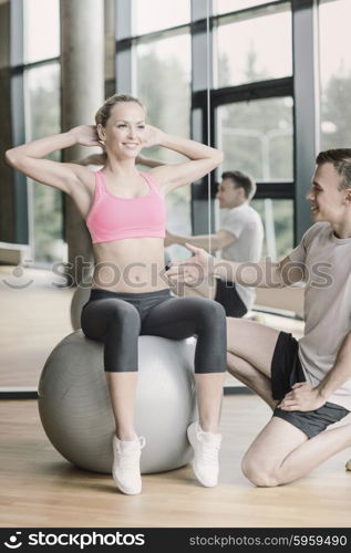 sport, fitness, lifestyle and people concept - smiling man and woman with exercise ball in gym