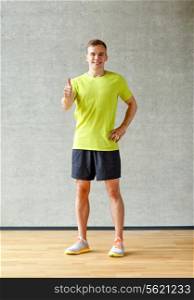 sport, fitness, lifestyle and people concept - smiling man showing thumbs up in gym