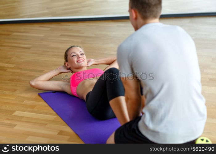 sport, fitness, lifestyle and people concept - smiling woman with male personal trainer exercising in gym