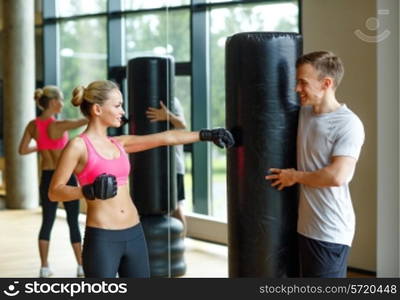 sport, fitness, lifestyle and people concept - smiling woman with personal trainer boxing in gym