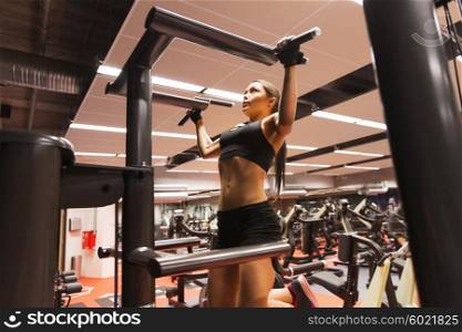 sport, fitness, lifestyle and people concept - woman exercising and doing pull-ups in gym