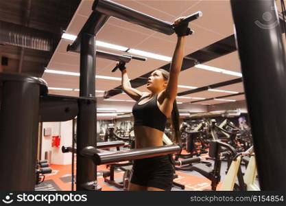 sport, fitness, lifestyle and people concept - woman exercising and doing pull-ups in gym