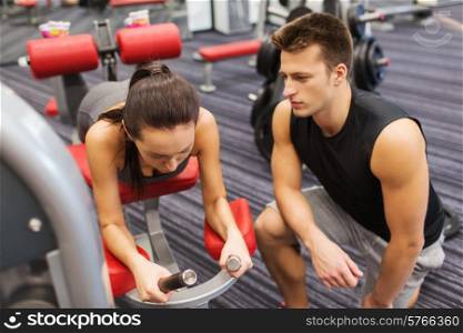 sport, fitness, lifestyle and people concept - young woman and personal trainer flexing leg muscles on gym machine