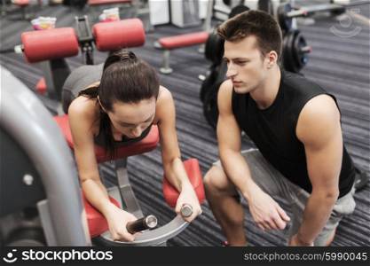 sport, fitness, lifestyle and people concept - young woman and personal trainer flexing leg muscles on gym machine