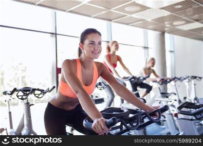 sport, fitness, lifestyle, equipment and people concept - group of women riding on exercise bike in gym