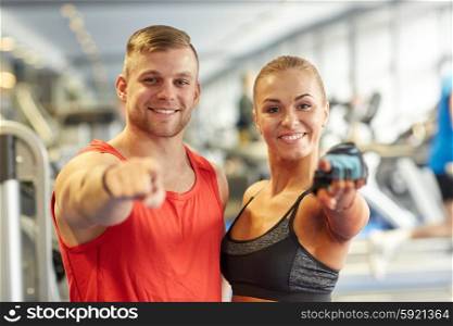sport, fitness, lifestyle, gesture and people concept - happy man and woman pointing finger to you in gym