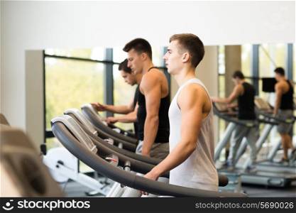 sport, fitness, lifestyle, technology and people concept - group of men exercising on treadmill in gym