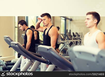 sport, fitness, lifestyle, technology and people concept - group of men exercising on treadmill in gym