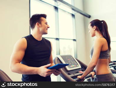 sport, fitness, lifestyle, technology and people concept - happy woman with trainer working out on treadmill in gym