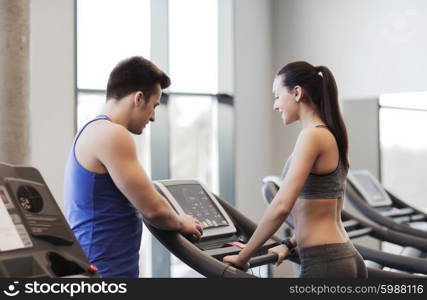 sport, fitness, lifestyle, technology and people concept - happy woman with trainer working out on treadmill in gym