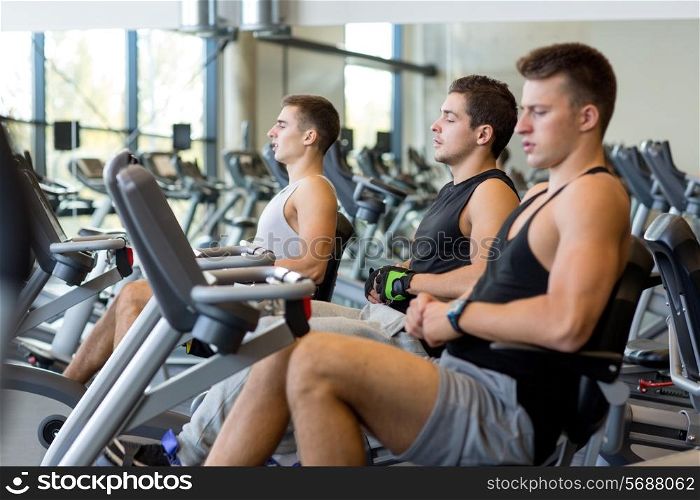 sport, fitness, lifestyle, technology and people concept - men working out on exercise bike in gym