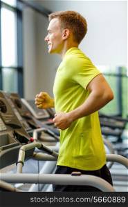 sport, fitness, lifestyle, technology and people concept - smiling man exercising on treadmill in gym