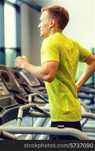 sport, fitness, lifestyle, technology and people concept - smiling man exercising on treadmill in gym