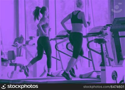 sport, fitness, lifestyle, technology and people concept - smiling woman exercising on treadmill in gym duo tone. woman exercising on treadmill in gym