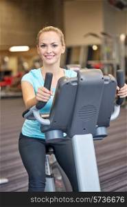 sport, fitness, lifestyle, technology and people concept - smiling woman exercising on exercise bike in gym