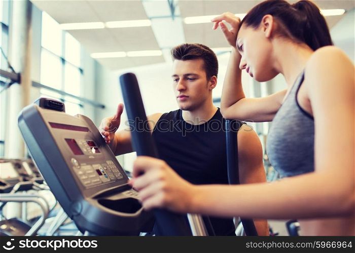 sport, fitness, lifestyle, technology and people concept - tired woman with trainer exercising on stepper in gym