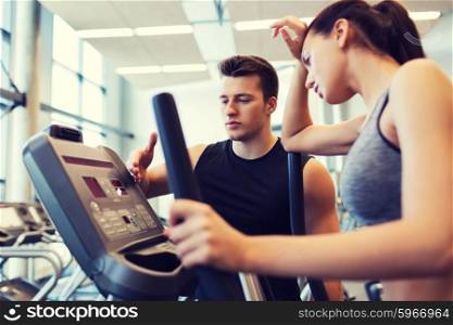 sport, fitness, lifestyle, technology and people concept - tired woman with trainer exercising on stepper in gym