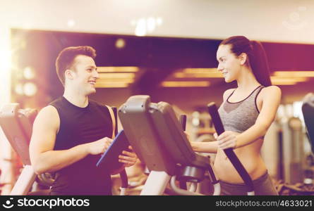 sport, fitness, lifestyle, technology and people concept - woman with trainer exercising on stepper in gym
