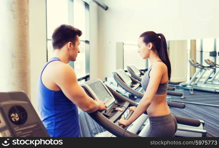 sport, fitness, lifestyle, technology and people concept - woman with trainer working out on treadmill in gym