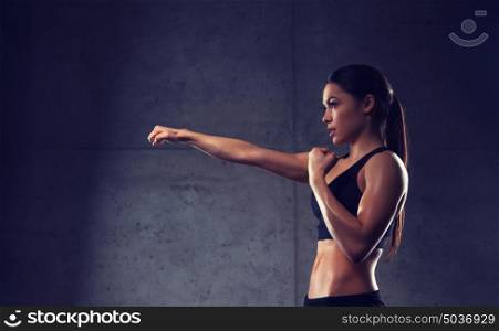 sport, fitness, martial arts and people concept - woman boxing and making punch in gym. woman boxing in gym