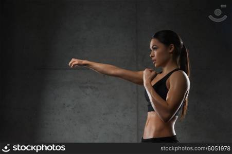 sport, fitness, martial arts and people concept - woman boxing and making punch in gym