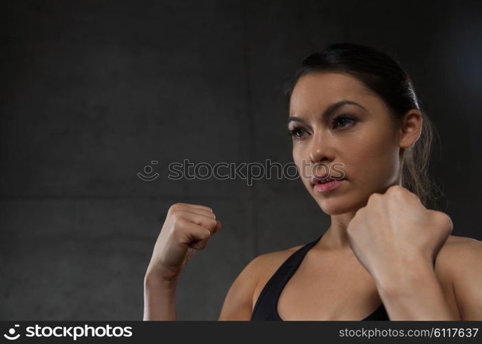 sport, fitness, martial arts and people concept - woman holding fists and fighting in gym