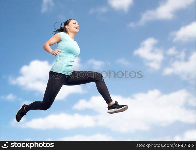 sport, fitness, motion and people concept - happy smiling young woman jumping in air over blue sky and clouds background