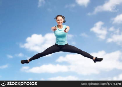 sport, fitness, motion and people concept - happy smiling young woman jumping in air over blue sky and clouds background